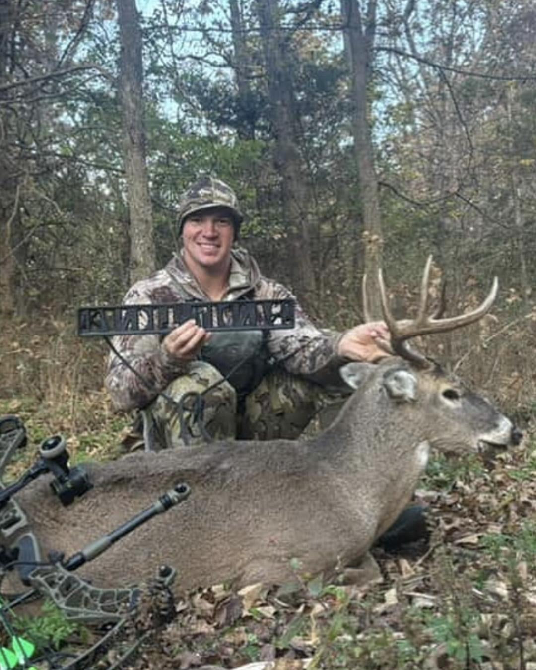 A customer posing with a deer they harvested holding a Bandit Climber by Raccoon Rigs.
